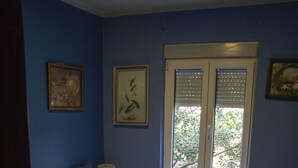 A bedroom with a bed, a window with blinds, and two framed pictures on the wall. - Apartment 99 Muses (Belgrade)