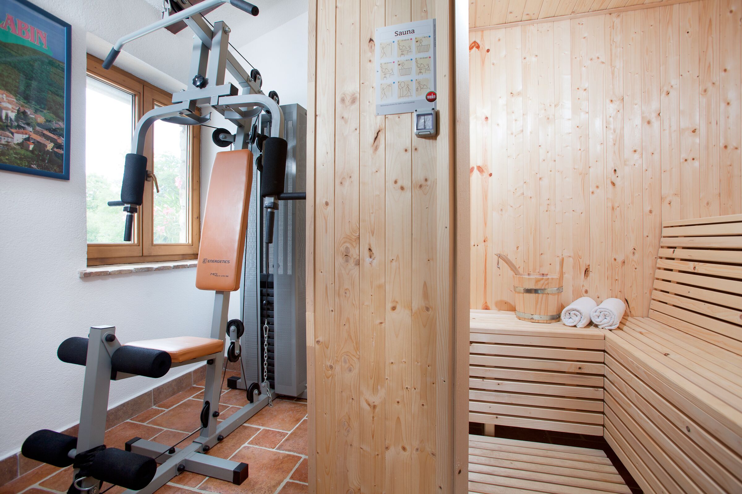 A gym with exercise equipment and a sauna area with benches and towels.