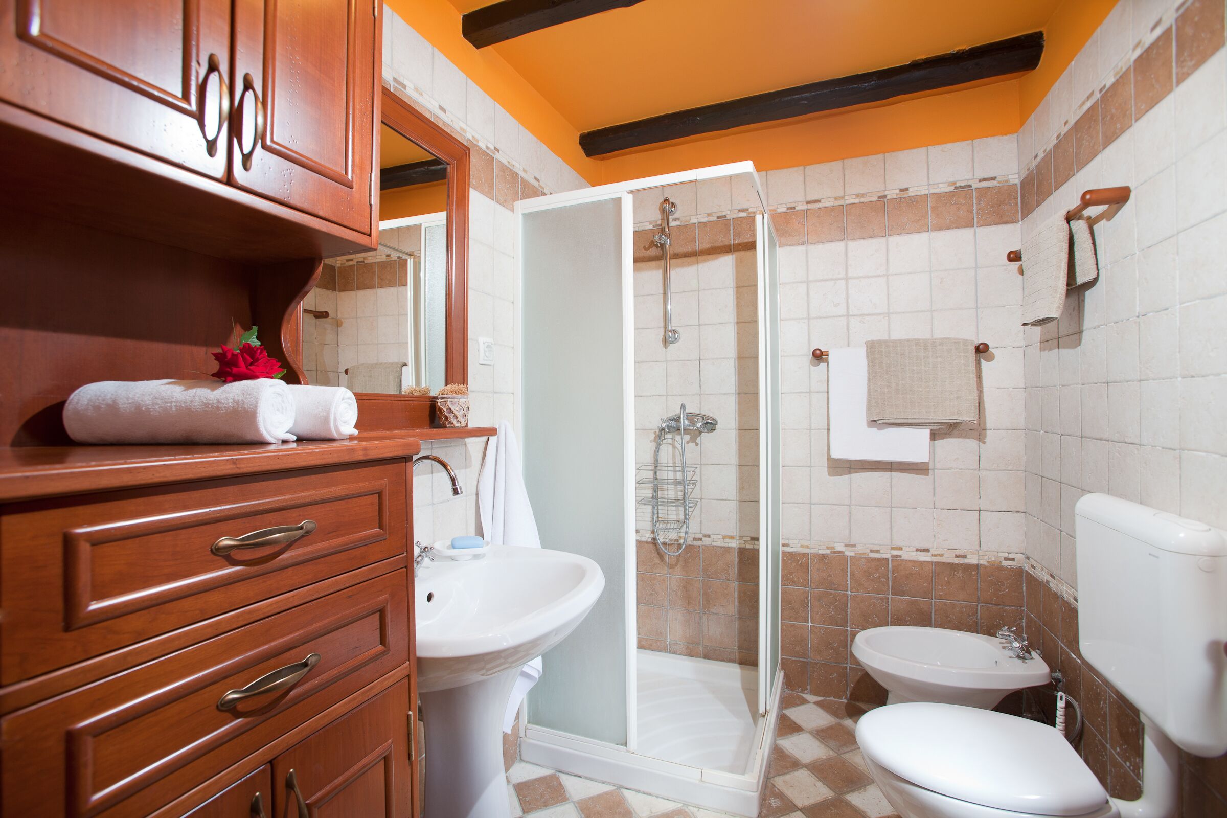A bathroom with a wooden vanity, a sink, a toilet, and a glass-enclosed shower.