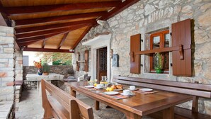 A stone-walled outdoor dining area with wooden benches and a table set for breakfast. - Wonderful, secluded, minutes from the beach, with 5 bedrooms (Labin)
