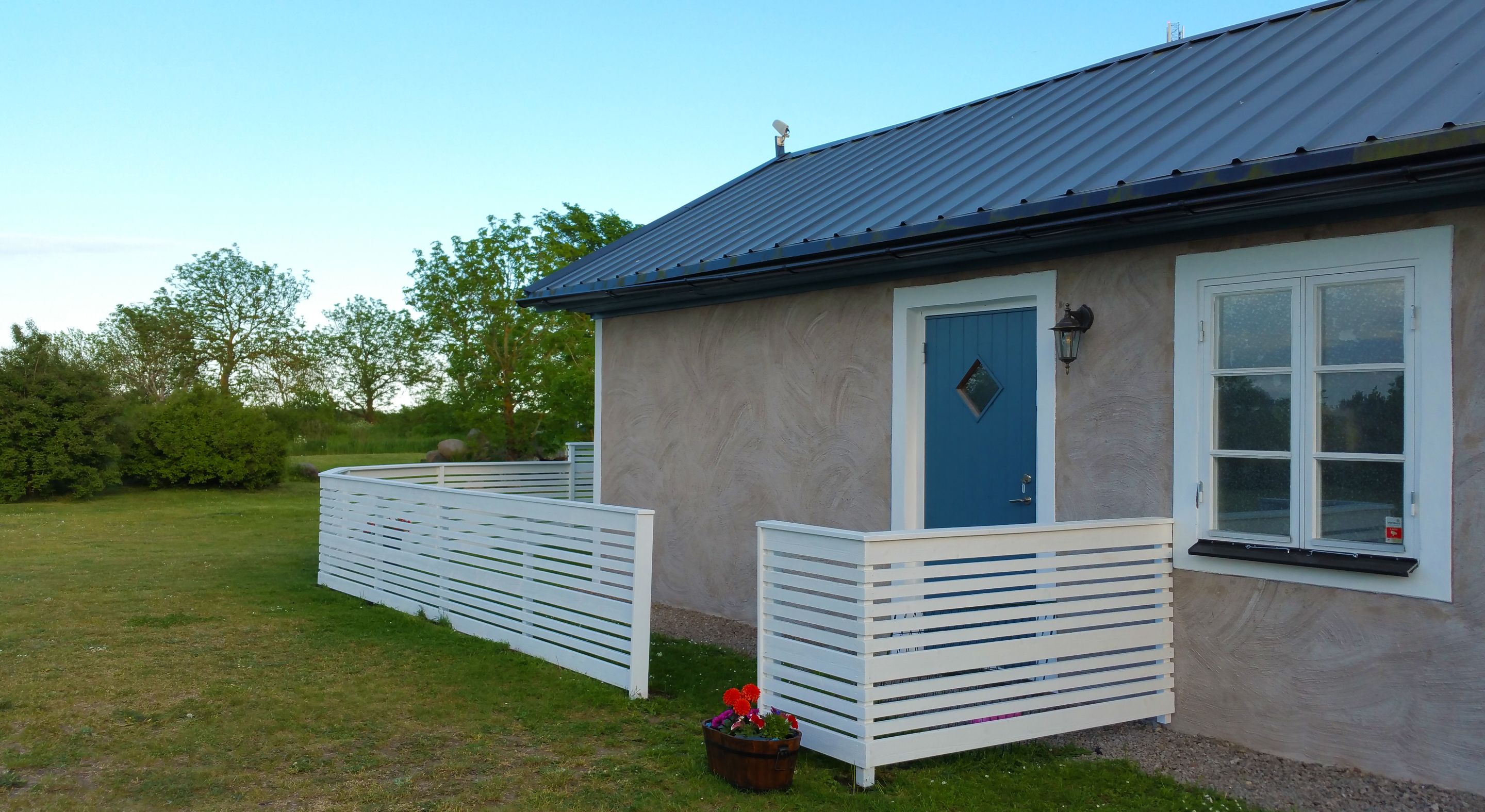 A single-story building with a blue door, a satellite dish, and a window with a black frame.