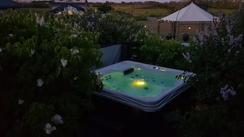 Relax in a serene garden oasis with a hot tub surrounded by lush greenery and a charming gazebo.