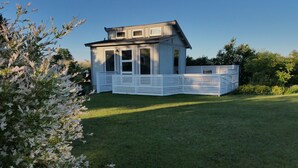 Ein modernes, zweistöckiges Haus mit weißer Fassade, großen Fenstern und einem umzäunten Garten.