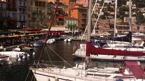 A marina with boats docked, a town in the background, and buildings with balconies.