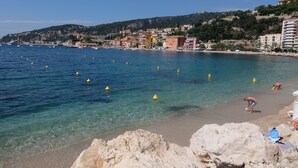 A coastal town with clear blue waters, rocky shoreline, and buildings along the coast.