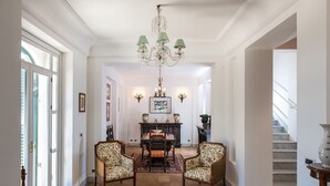 Un pasillo espacioso con comedor, que incluye una araña, una mesa de comedor con sillas y una escalera.