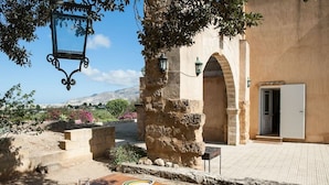 Un espacio de comedor al aire libre con una mesa dispuesta para cuatro, un muro de piedra y vistas a un paisaje montañoso.