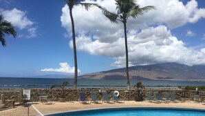 A pool with lounge chairs and a view of the ocean and mountains. - Stunning Oceanfront, 2BR/2BA, Gorgeous Ocean & Mt. Views, Premium A/C (Kihei)