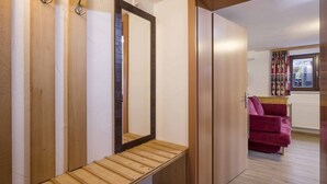 A room with wooden flooring, a bench, a mirror, and a red sofa.