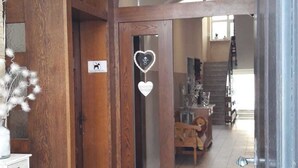 A spacious hallway with wooden doors and a tiled floor, leading to a dining area with a high ceiling and recessed lighting. - Zum Goldenen Löwen (Moosbach)