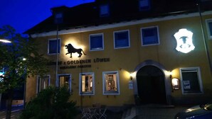 A building with a lion silhouette and the name "Fz Goldenen Lower" illuminated on the facade. - Zum Goldenen Löwen (Moosbach)
