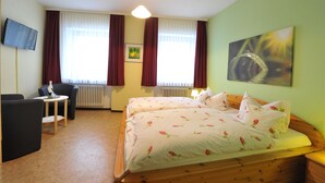A hotel room with a bed, two chairs, a small table, a TV, and a painting on the wall. - Zum Goldenen Löwen (Moosbach)