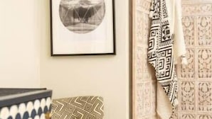 A room with a patterned chair, a framed picture on the wall, a patterned sofa, and a decorative chair with a patterned cloth. - Boho Lux (Atlanta)