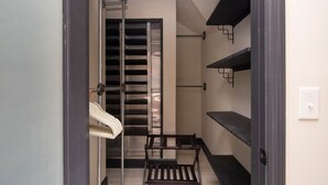 A narrow hallway with a metal ladder, a wooden bench, and black shelves against the wall. - Boho Lux (Atlanta)