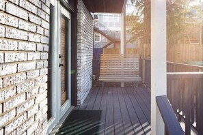 A wooden deck with a bench, a door, and a staircase leading to an upper level. - Boho Lux (Atlanta)