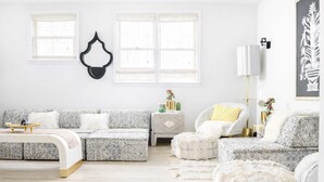 A modern living room with a sofa, ottomans, a side table, and a chair. - Boho Lux (Atlanta)