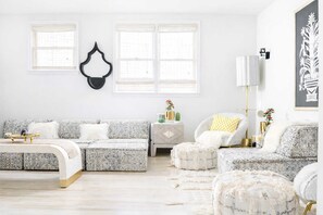 Una sala de estar moderna con un sofá, otomanas, una mesita auxiliar y una silla.
