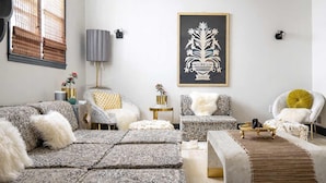 A modern living room with patterned sofas, a coffee table, and a decorative wall piece. - Boho Lux (Atlanta)