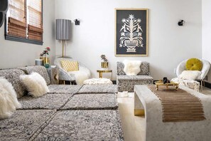 A modern living room with patterned sofas, a coffee table, and a decorative wall piece. - Boho Lux (Atlanta)
