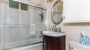 A bathroom with a glass-enclosed shower, a white sink, a wooden vanity, and a toilet. - Perfect Location | Fantastic Home | Near Beach! (Oceanside)
