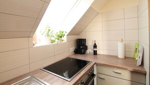 Una cocina moderna con estufa integrada, cafetera y una botella de vino.