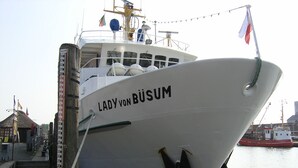 Un barco blanco grande llamado "Lady von Büsum" atracado en un muelle.