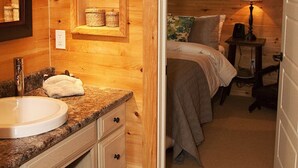 A wooden cabin-style room with a bathroom, a bed, and a small table with a lamp. - Relax, Connect & Enjoy with AC at private Oasis. (Long Creek)