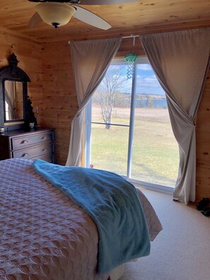A bedroom with a bed, a dresser, a mirror, and a window with curtains.