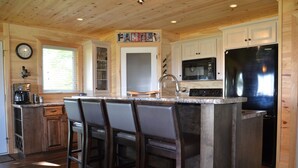 A kitchen with wooden cabinets, a stainless steel refrigerator, and a bar area with stools. - Relax, Connect & Enjoy with AC at private Oasis. (Long Creek)