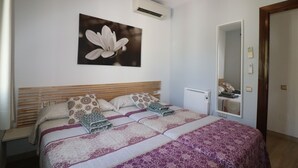 Camera da letto con un letto grande, condizionatore d'aria a parete e uno specchio che riflette l'ambiente.