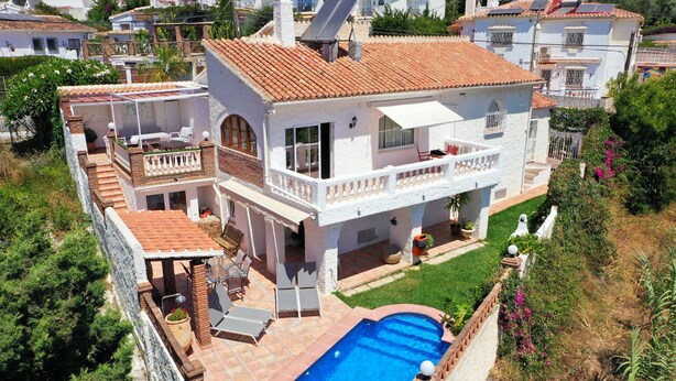 Una casa a due piani con piscina, un balcone e un giardino.