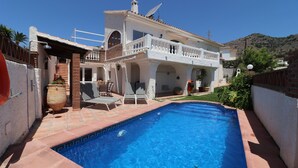 Una casa a due piani con piscina, un balcone e un'antenna parabolica.