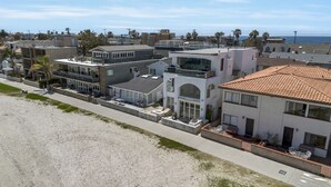 Ein Küstenwohngebiet mit modernen Häusern, ein Strand im Vordergrund und freie Sicht auf den Ozean.