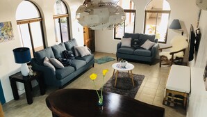 Uma sala de estar com uma mesa de jantar de madeira escura, dois sofás, uma pequena mesa de centro e um abajur decorativo.