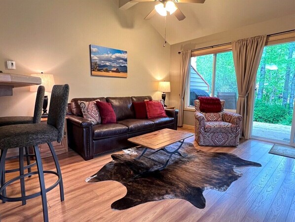 A living room with a leather sofa, patterned armchair, and a unique animal hide rug.