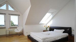 A bedroom with a bed, a chair, a small table, and a window. - homefortimes Frankfurt-Airport (Langen)