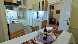 A compact kitchen with a dining area, featuring a table set for two with wine glasses and a bottle. - Apartment Markovic (Belgrade)