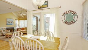 En matplats med ett träbord och vita stolar, en kristallkrona och en väggdekoration med texten ”Paradiset är funnet”.