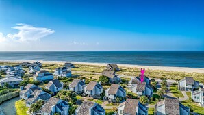 Ett bostadsområde vid kusten med hus, en strand och en klar himmel.