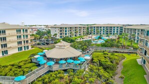 Un resort con varias construcciones, un área de piscina central y un pabellón con sombrillas.