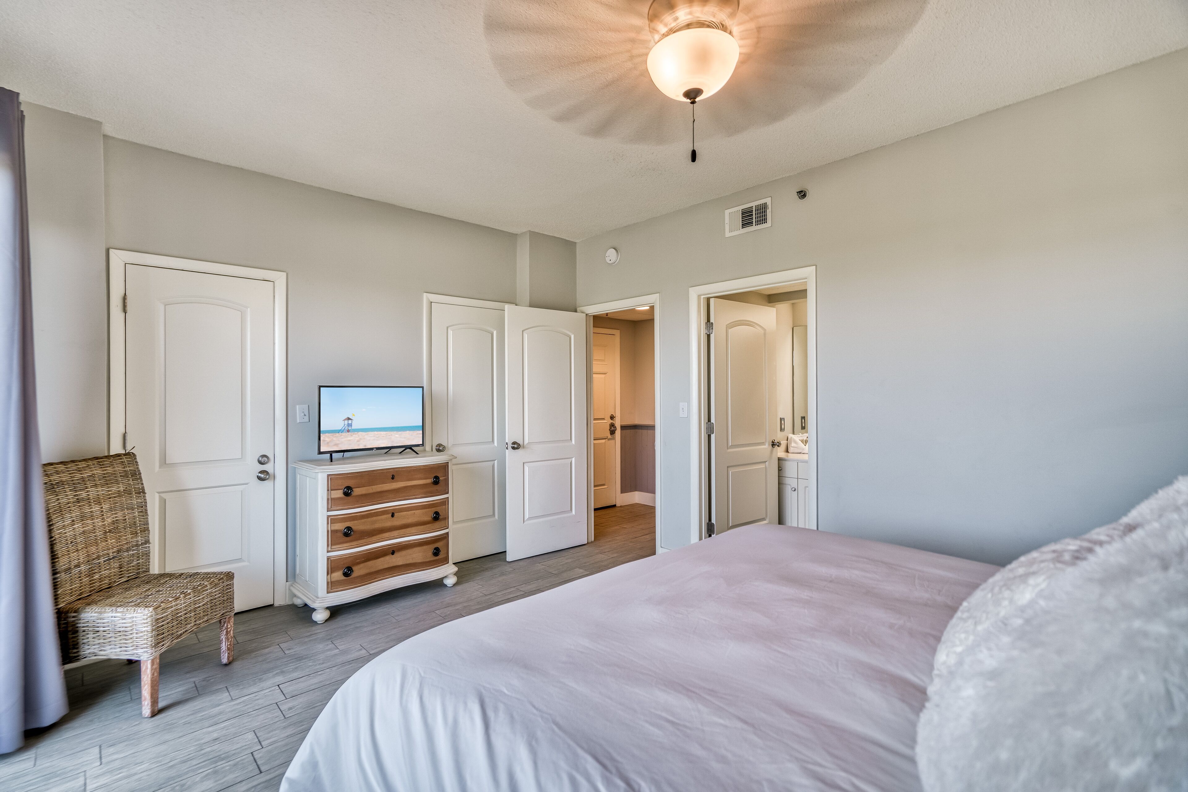 Een slaapkamer met een bed, een televisie, een dressoir en een stoel.