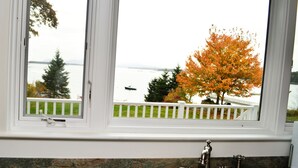 A bathroom with a view of a lake, a white railing, and a stone countertop. - Classic and Spacious Maine Waterfront Retreat (Sullivan)