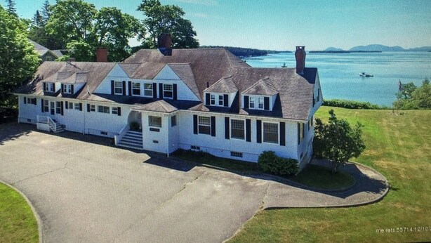 A large, two-story house with a wrap-around porch and a view of a lake. - Classic and Spacious Maine Waterfront Retreat (Sullivan)