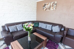 A modern living room with a brown leather sofa, a glass coffee table, and a vase of flowers.