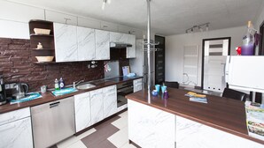 Une cuisine moderne avec des meubles de couleur blanche en marbre, un îlot central et une hotte de cuisine en acier inoxydable.