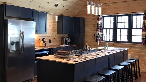 A modern kitchen with a central island, wooden ceiling beams, and a large window. - Cozy Cabin in Pittsburg NH  - DIRECT SNOWMOBILE & ATV TRAIL ACCESS (Pittsburg)