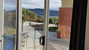 Varanda com vista para uma área residencial, uma parede de tijolos e uma cerca de madeira.