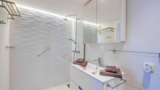 A modern bathroom with a glass shower enclosure, a white vanity with a mirror, and a glass shelf. - Sa Maniga - sunny modern apartment, 3floors, on the beach up to 3per. WLAN incl. (Cala Millor)