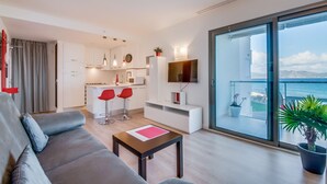 A modern living room with a grey sofa, a coffee table, and a balcony with a view of the sea. - Sa Maniga - sunny modern apartment, 3floors, on the beach up to 3per. WLAN incl. (Cala Millor)