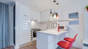 A modern kitchen with white cabinetry, a central island, and red bar stools.